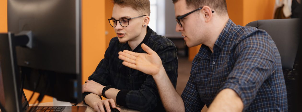 Full concentration at work. Group of young business people working and communicating while sitting at the office desk together with colleagues sitting in the background