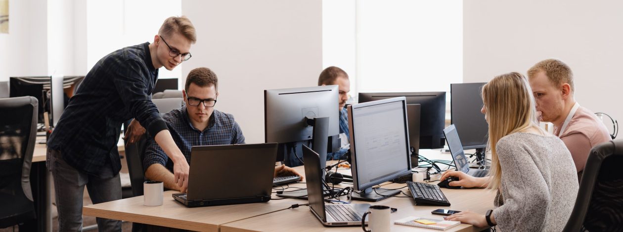 Full concentration at work. Group of young business people working and communicating while sitting at the office desk together with colleagues sitting in the background